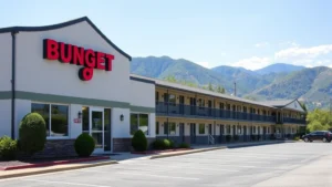 Modern budget motel exterior with clean facade and parking area, mountain landscape visible in background, daytime photography, Tennessee mountain setting, residential hospitality building with simple design elements
