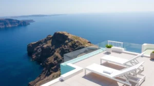 Luxurious Mediterranean coastal hotel terrace with white lounge chairs, sea view infinity perspective, dramatic clifftop setting overlooking turquoise water and distant coastline