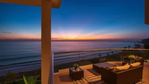 Modern hotel balcony overlooking coastal ocean view at sunset with comfortable seating and ambient lighting, professional resort photography