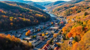 Scenic aerial view of historic Jim Thorpe Pennsylvania town nestled in forested Pocono Mountains with Lehigh River winding through valley, autumn foliage visible, Victorian buildings downtown, residential neighborhoods on hillsides