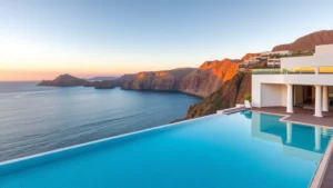 Luxury oceanfront hotel resort in Madeira with modern architecture, infinity pool overlooking Atlantic Ocean, white-washed building with contemporary design, golden hour sunset lighting, calm blue waters below dramatic volcanic cliffs, no text or signage visible
