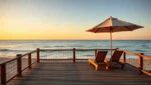Oceanfront wooden deck overlooking calm Atlantic Ocean with beach chairs and umbrella, golden hour lighting, peaceful coastal atmosphere, no people visible