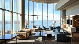 Modern hotel lobby with comfortable seating, floor-to-ceiling windows overlooking San Diego bay, contemporary furniture, natural lighting, upscale ambiance, no people visible