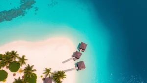 Aerial view of luxury beachfront resort with overwater bungalows, turquoise Caribbean water, white sand beach, and palm trees, tropical paradise setting, daytime, crystal clear water